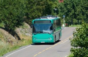 Green bus driving through an area with lush vegetation