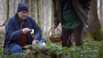 Zwei Männer mit Körben finden in einem Wald menschliche Knochen.