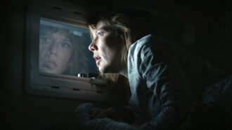 Eine Frau schaut nachts aus dem Fenster und sieht verdächtige Personen.