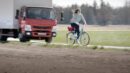Eine Frau flüchtet mit ihrem Fahrrad vor einem LKW.