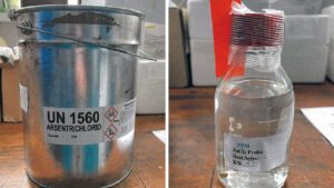 Behälter mit Arsentrichlorid. Links in einem Metallkanister, rechts in einem Fläschchen.