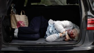 Eine Frau liegt im Kofferraum eines schwarzen Audis neben Einkaufstüten. Sie ist im Gesicht blutverschmiert und mit Panzertape gefesselt und geknebelt.