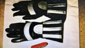 Schwarze Motorradhandschuhe mit silbernen Reflektoren und ein rotes Schweizer Taschenmesser.