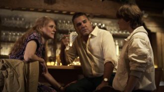 Ein Mädchen spricht mit einer Frau, die mit einem Mann an einer Theke sitzt.