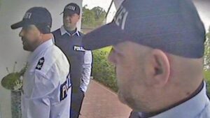 Drei Männer stehen in Polizei-Verkleidung vor einer Haustür.