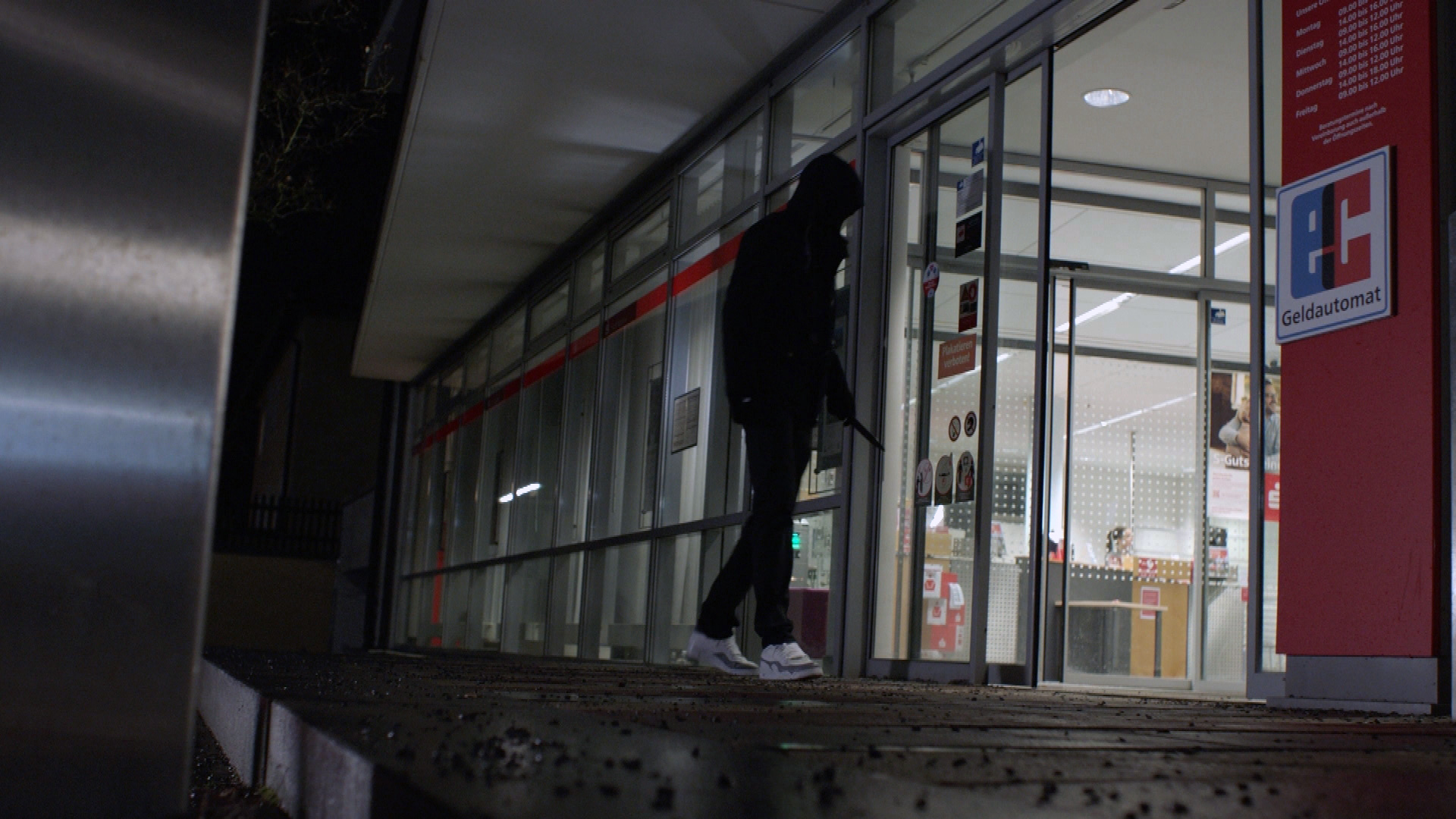 Ein vermummter Mann tritt in eine Sparkassenfiliale ein. Er hält ein Messer in der Hand.