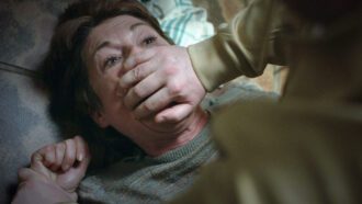 Ein Mann überwältigt eine Frau. Er hält ihr mit seiner Hand den Mund zu.