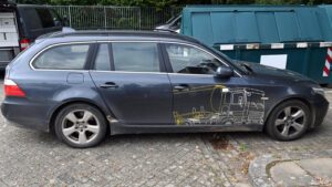 Ein dunkelgrauer Kombi mit einem aufgemalten gelb-weißen Lkw.