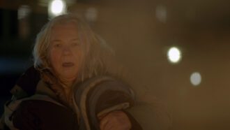 Eine ältere, obdachlose Frau flüchtet aus ihrem brennenden Zeltlager.