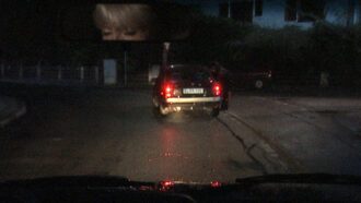 Eine junge Frau steht an einem Auto.