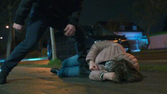 Eine Frau liegt verletzt auf der Straße. Der Täter steht neben ihr.