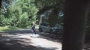 Eine Frau in Sportkleidung joggt auf einem Parkplatz im Wald.