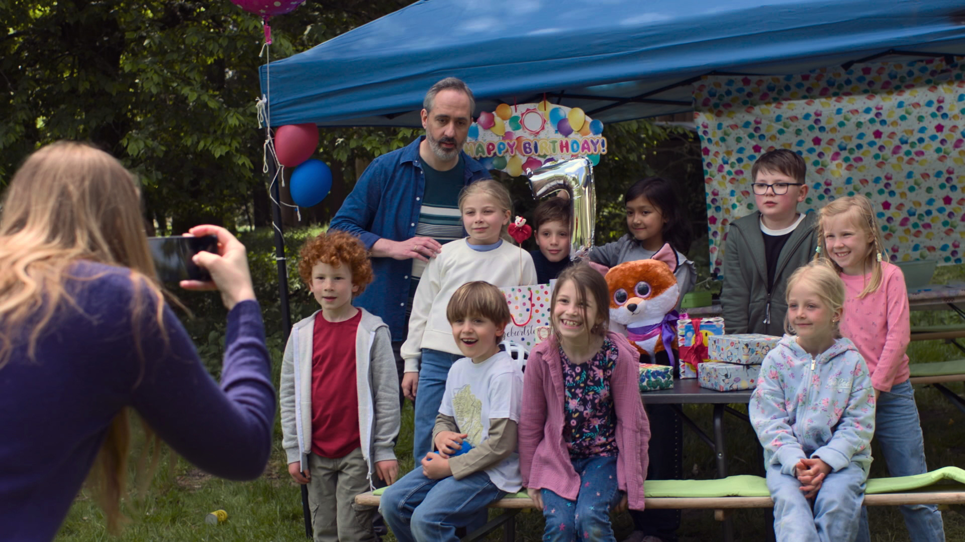 Kinder bei einer Geburtstagsfeier, die lachend fotografiert werden.